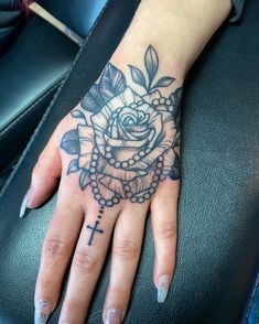 a woman's hand with a cross and rose tattoo on the middle of it