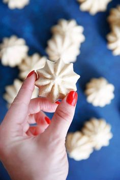 a woman's hand is holding a small white object in front of some cookies