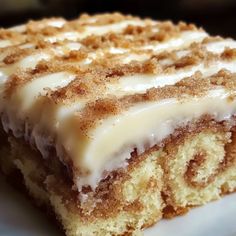 a close up of a piece of cake on a plate with white icing and cinnamon crumbs