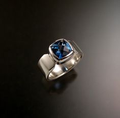 "9mm Cushion cut London Blue Topaz is bezel-set with 8mm wide by 2mm thick rectangular band. This is an expertly cut and deep blue natural gem. Topaz hardness is Mohs 8. Pictured ring is size 9 1/2. Specify you ring size in a \"note to seller\" at check out." Modern Rectangular Blue Sapphire Ring, Modern Blue Rectangular Sapphire Ring, Modern Blue Sapphire Ring With Tension Setting, Modern Blue Sapphire Ring With Bezel Setting, Modern Rectangular Blue Topaz Ring, Elegant Blue Topaz Cushion Cut Jewelry, Blue Cushion Cut Topaz Ring Gift, Gift Blue Square Cut Topaz Ring, Luxury Square-cut Topaz Ring