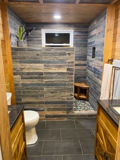 a bathroom with wood paneled walls and tile flooring is shown in this image