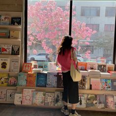 a woman standing in front of a window looking at books