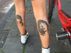 two people with tattoos on their legs standing next to a bike