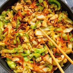 stir fry with vegetables and chopsticks in a skillet on a gray surface