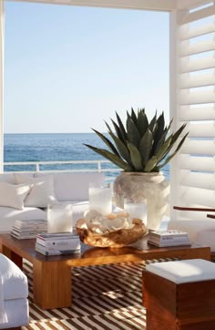 a living room filled with white furniture next to the ocean