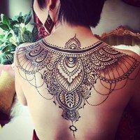 the back of a woman's shoulder with an intricate tattoo design on her upper