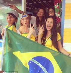 a group of young people standing next to each other holding a brazil flag and making the peace sign