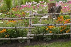 a wooden fence surrounded by flowers and rocks