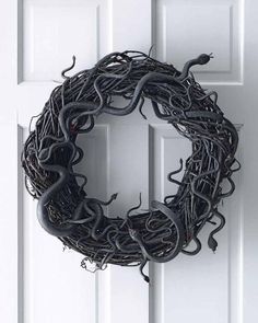 a wreath made out of wire and snakes hanging from it's sides on a door