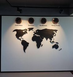 a white wall with three clocks and a world map on it