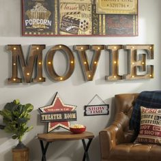 there is a movie sign on the wall next to a leather chair and table with a potted plant