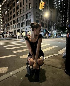 a woman kneeling down on the side of a street