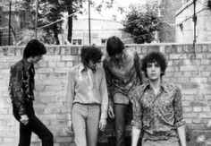 an old black and white photo of the rolling stones in front of a brick wall