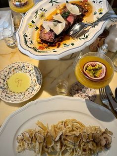 a table topped with plates of food and glasses of wine on top of a table