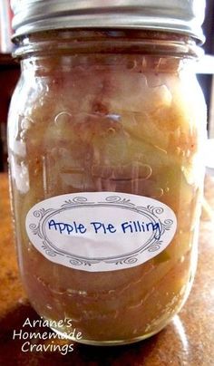 an apple pie filling in a glass jar on a wooden counter top with a label that says apple pie filling