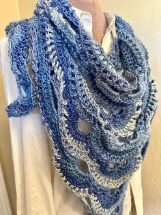 a blue and white crocheted scarf hanging on a mannequin