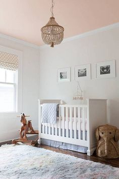 a baby's room with pink walls and white furniture