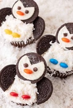 four oreo cookies with frosting decorated like penguins on top of white shredded rice