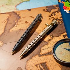 two pens and a compass sitting on top of a map