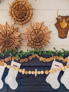 christmas stockings hanging from a mantel decorated with orange slices and cinnamons, along with other holiday decorations