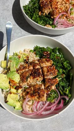 two bowls filled with meat and vegetables on top of a white countertop next to each other