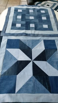 two quilted bedspreads sitting on top of each other with blue and white designs