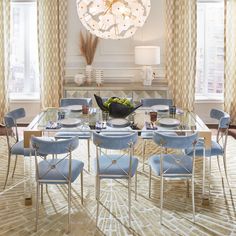 a dining room table with blue chairs and a chandelier hanging from the ceiling