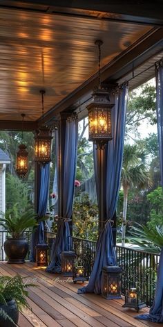 an outdoor covered porch with blue curtains and lanterns