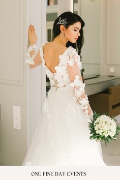 a woman in a white wedding dress is holding her hand out to the side while looking at herself