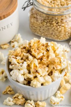 a white bowl filled with popcorn next to two jars