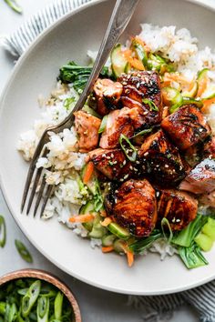 a white bowl filled with rice and meat on top of a table next to vegetables