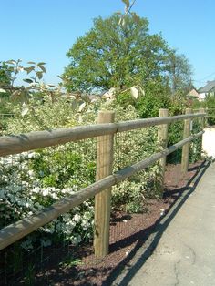 the fence is made of wood and has white flowers growing on it, along with other plants