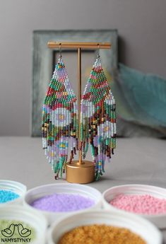 the beaded earrings are on display next to bowls of colored beads and a wooden frame