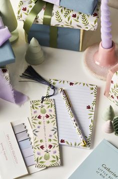 various stationery items displayed on table with notepads and gift boxes in background