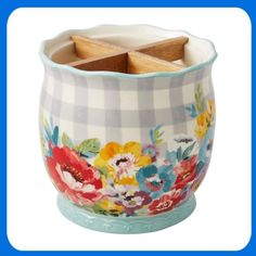 a bowl with wooden spoons in it and flowers on the inside, sitting on a white background