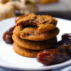 a stack of cookies sitting on top of a white plate next to raisins