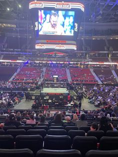 an arena filled with lots of people sitting in chairs and watching a game on the big screen