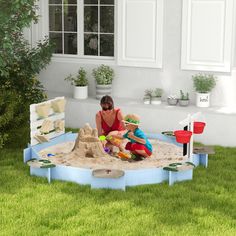 a woman and child playing in a sandbox on the lawn with their toys outside