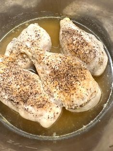 three pieces of chicken in a pan with mustard and seasoning on top, ready to be cooked