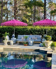 an outdoor pool with chairs, umbrellas and potted plants next to the pool