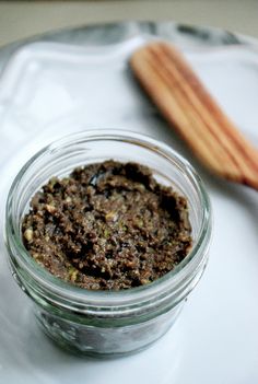 a glass jar filled with food sitting on top of a white plate next to a wooden spoon