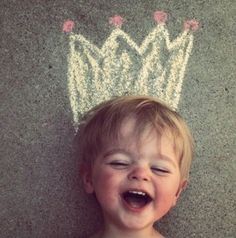 a little boy laying on the ground with a crown drawn on it's head