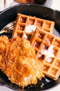 fried chicken and waffles on a black plate with a fork next to it