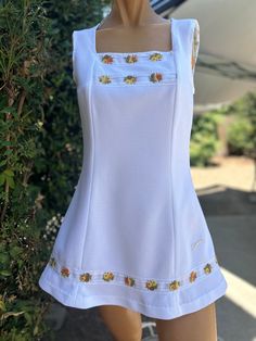 Here is a vintage 1970s Slazenger tennis dress.No size.Following are the measurements.Bust 34",Waist 32",Hips full,Length measured from top of shoulder to hem 30"long.Zips up the back.Made out of a white polyester fabric.Peach & yellow colored flowers trim around bodice and hem.Nice vintage condition.Please take special consideration of measurements. 1970s sizing was much smaller than today's standards.Tennis dresses were very short not like a regular dress. So please take special note of length Vintage Tennis Dress, Spring Cotton Tennis Dress, Cotton Tennis Dress For Spring, Sleeveless Spring Tennis Dress, Sleeveless Tennis Dress For Spring, Casual Fitted Spring Tennis Dress, Casual Fitted Tennis Dress, White Cotton Tennis Dress, Fitted Tennis Dress For Spring