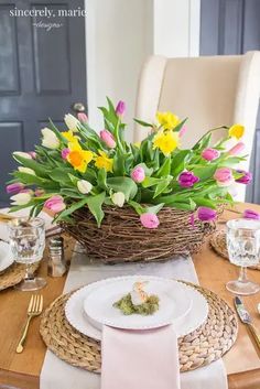 the table is set with flowers in a basket and place settings for two people to sit at