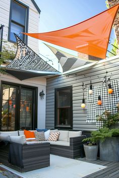 an outdoor living area with couches, potted plants and orange flags hanging from the roof