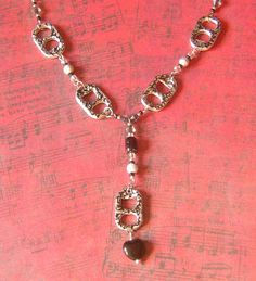 a silver necklace with a heart shaped bead on it and a chain attached to the clasp