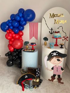 a birthday party with balloons, cake and pirate decorations on the table in front of an arch