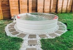 an outdoor hot tub in the middle of a yard with stepping stones and gravel around it