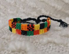 a multicolored bracelet with tassels on top of a white cloth covered surface